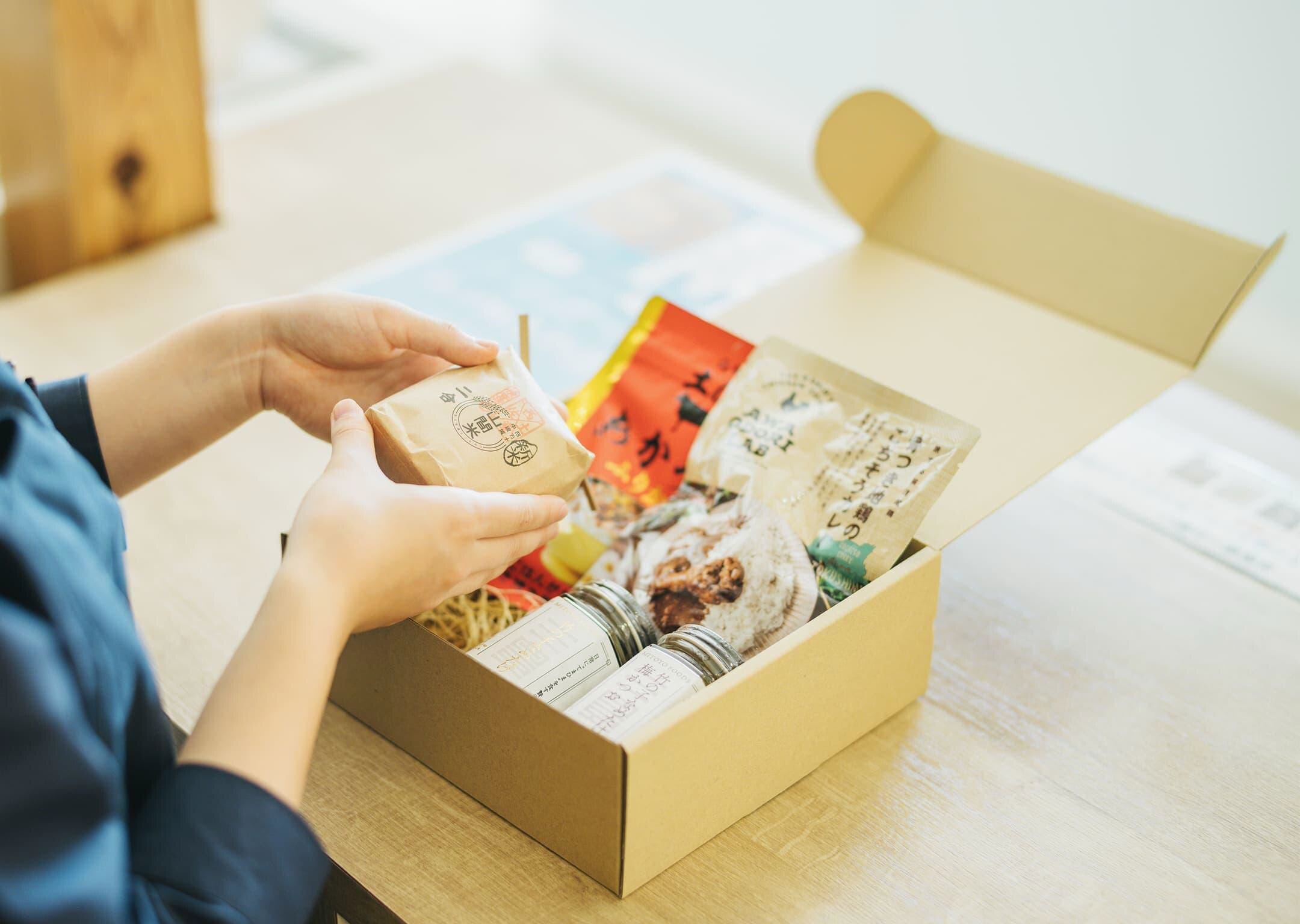 ギフト用に箱詰めされた食品の詰め合わせを手に取る様子